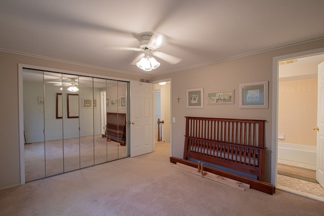 bedroom with carpet floors, ornamental molding, a ceiling fan, and a closet