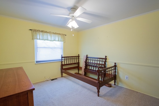 carpeted bedroom featuring crown molding, ceiling fan, visible vents, and baseboards