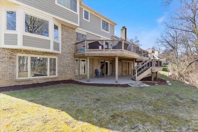 back of property featuring brick siding, a yard, a patio, and a deck