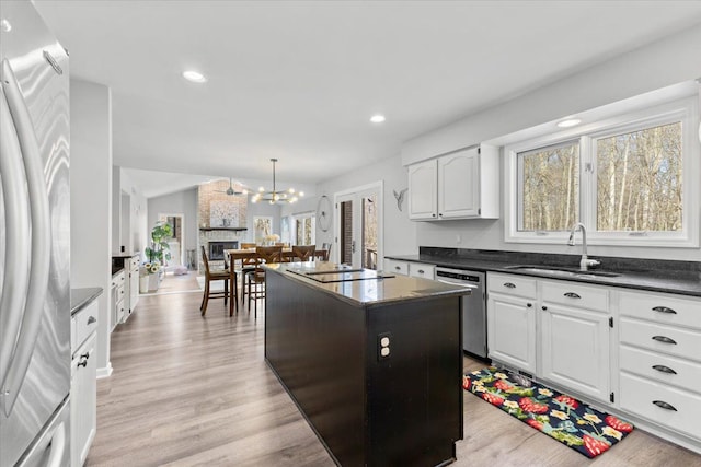 kitchen with dark countertops, a center island, stainless steel appliances, and a sink