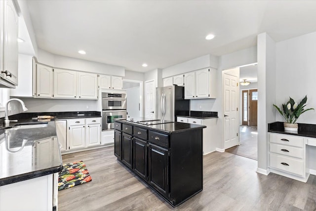 kitchen featuring white cabinets, dark cabinetry, stainless steel appliances, and a sink