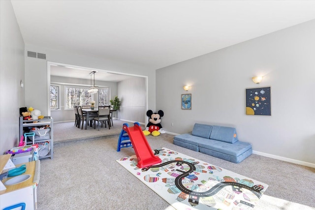 living area featuring carpet floors, visible vents, and baseboards