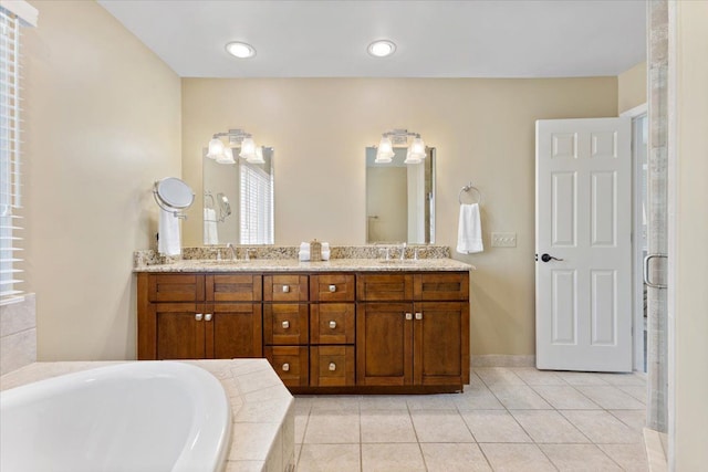 full bath with tile patterned floors, tiled tub, a sink, and double vanity