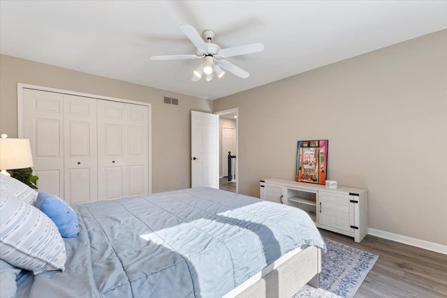 bedroom with baseboards, visible vents, a ceiling fan, wood finished floors, and a closet
