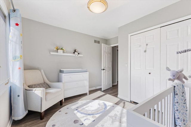 bedroom featuring baseboards, wood finished floors, visible vents, and a closet