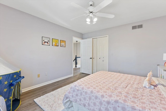 bedroom featuring wood finished floors, visible vents, a closet, baseboards, and ceiling fan