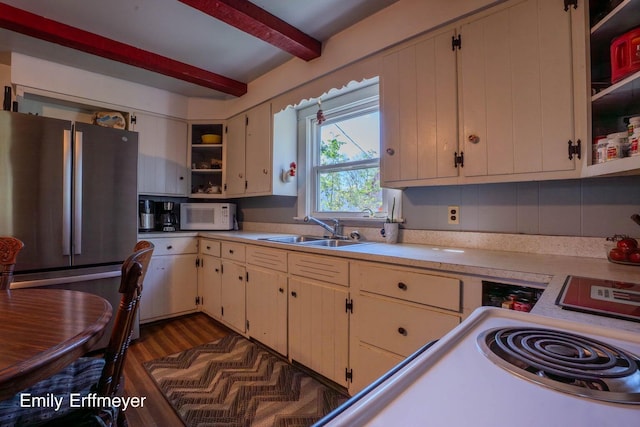 kitchen with open shelves, light countertops, a sink, freestanding refrigerator, and white microwave