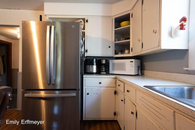 kitchen with light countertops, freestanding refrigerator, white microwave, and dark wood finished floors