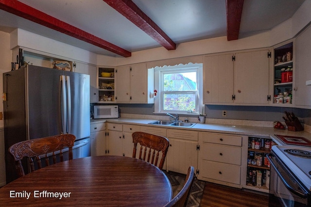 kitchen featuring open shelves, a sink, beamed ceiling, white microwave, and freestanding refrigerator