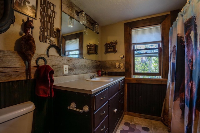 full bath with tile patterned floors, vanity, a wealth of natural light, and toilet