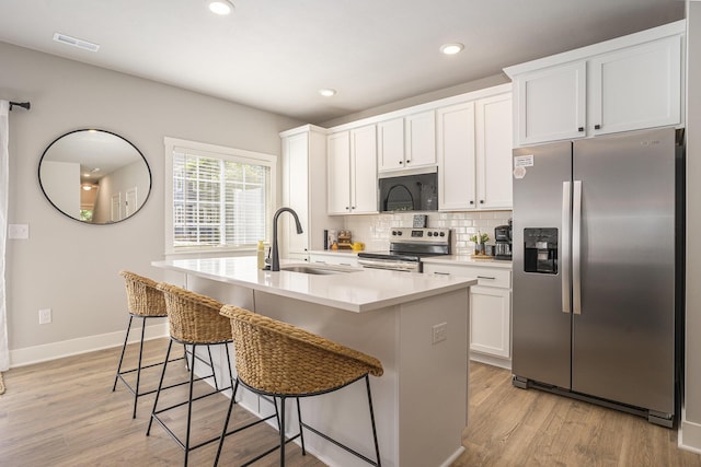 742 Ravine Ln, South Haven, MI 49090 - kitchen with a sink, a center island with sink, visible vents, backsplash, and appliances with stainless steel finishes