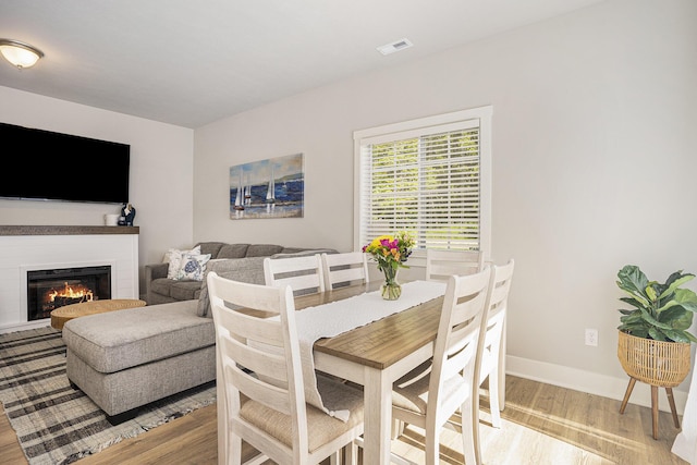 742 Ravine Ln, South Haven, MI 49090 - dining area with a glass covered fireplace, visible vents, light wood finished floors, and baseboards