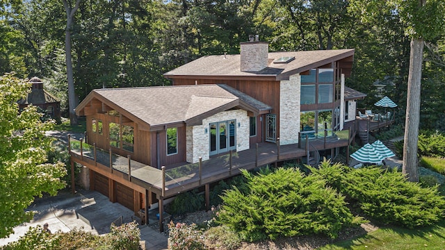 5788 M 63, Coloma, MI 49038 - back of house featuring a chimney, an attached garage, stone siding, roof with shingles, and a deck