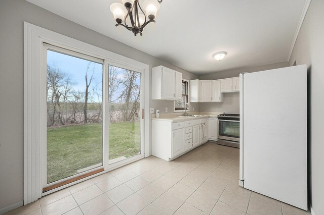 kitchen featuring light countertops, a sink, freestanding refrigerator, a chandelier, and stainless steel electric range oven