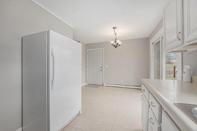 kitchen with a baseboard radiator, light tile patterned flooring, a chandelier, light countertops, and freestanding refrigerator