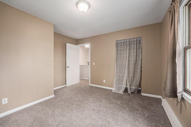 unfurnished bedroom featuring baseboard heating, baseboards, and carpet