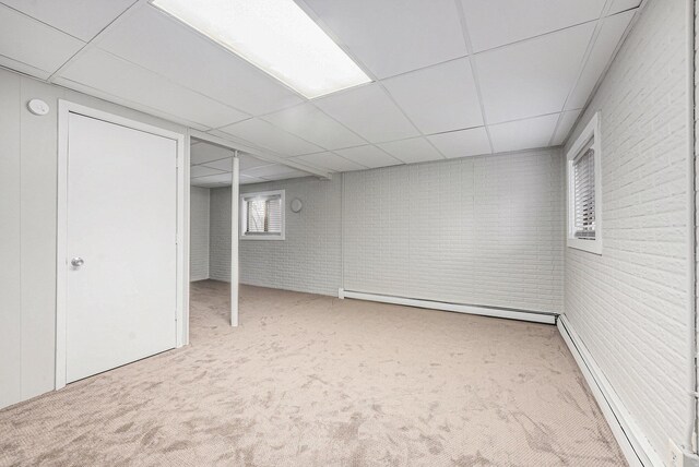 below grade area featuring a baseboard radiator, carpet floors, baseboard heating, and a paneled ceiling