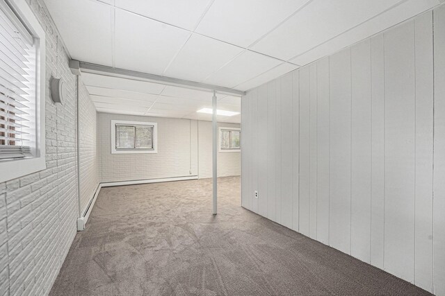 below grade area with brick wall, carpet flooring, and a drop ceiling