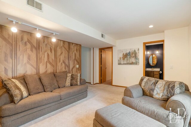 living area featuring light carpet, track lighting, visible vents, and baseboards
