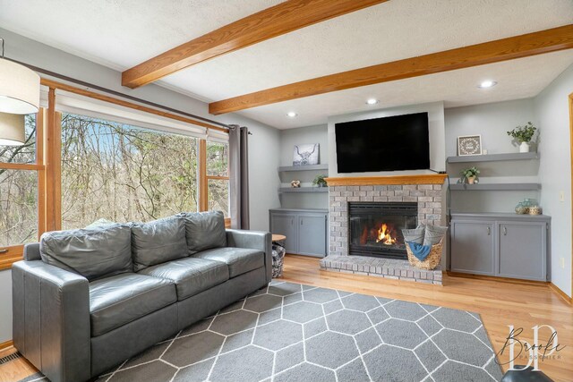living room featuring beamed ceiling, wood finished floors, and a fireplace
