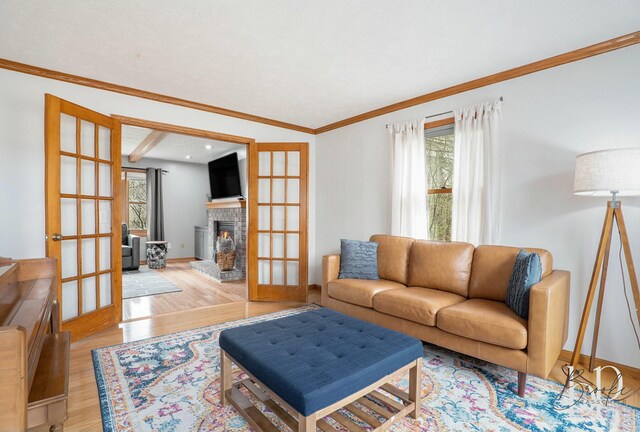 living room with baseboards, ornamental molding, a lit fireplace, and wood finished floors