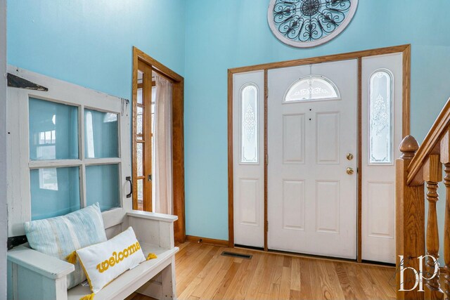 entryway with stairway, baseboards, wood finished floors, and visible vents