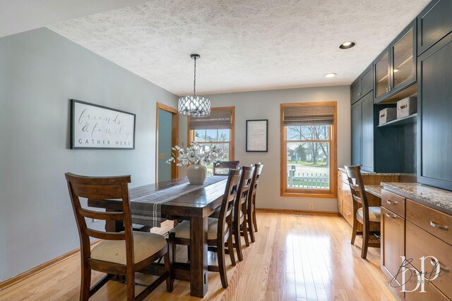 dining space with a textured ceiling, light wood-style floors, an inviting chandelier, baseboards, and recessed lighting