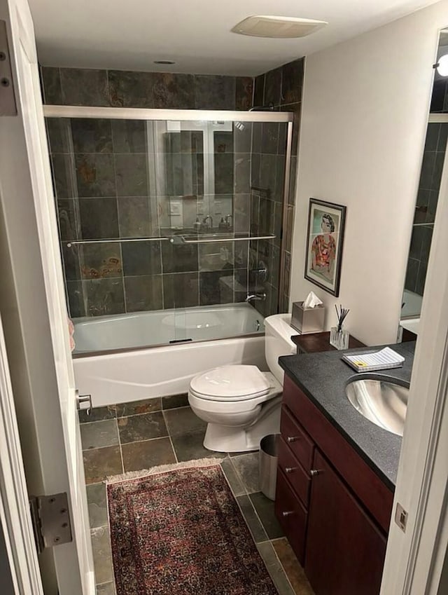 full bath with vanity, bath / shower combo with glass door, and toilet