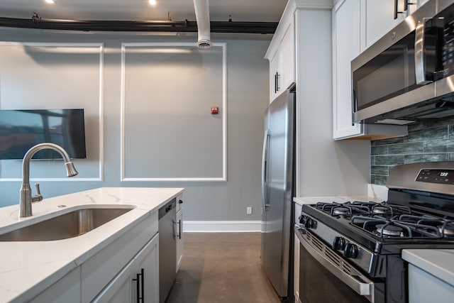 kitchen with light stone counters, a sink, concrete floors, tasteful backsplash, and appliances with stainless steel finishes