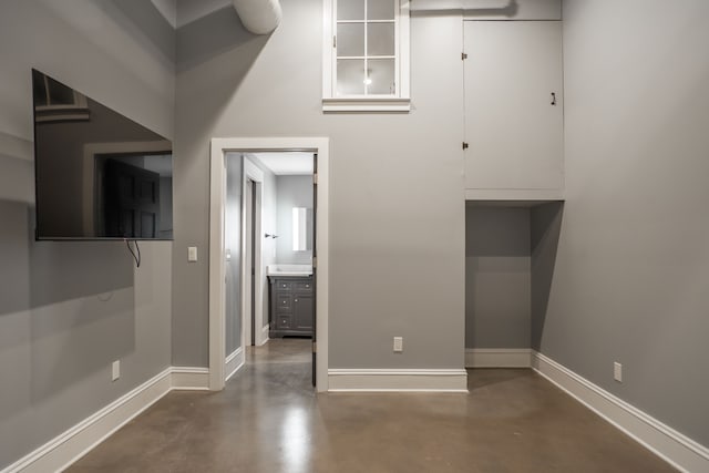 unfurnished bedroom featuring baseboards and finished concrete flooring