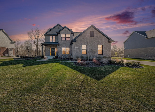view of front of home featuring a yard and brick siding