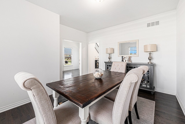 dining room featuring visible vents, baseboards, dark wood finished floors, and a fireplace