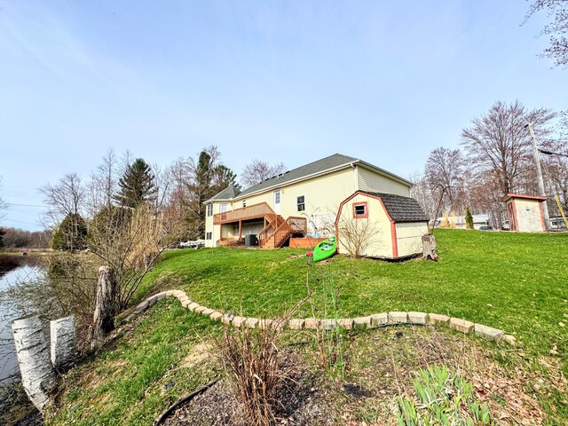 exterior space with stairway, an outbuilding, a lawn, a storage unit, and a deck