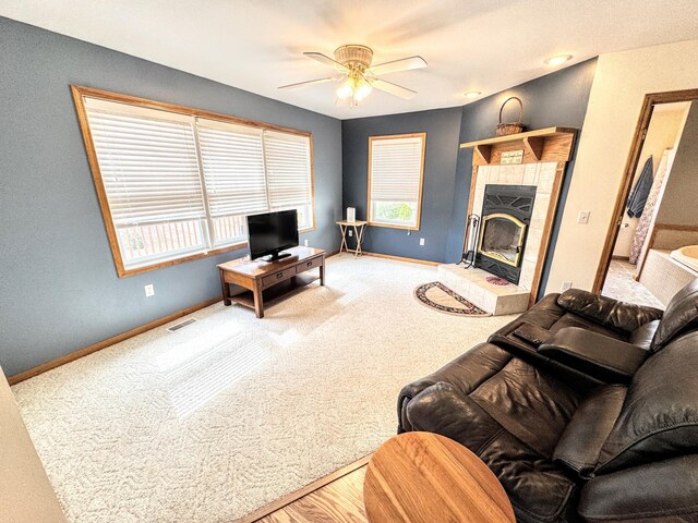 carpeted living room featuring baseboards, a ceiling fan, visible vents, and a wealth of natural light
