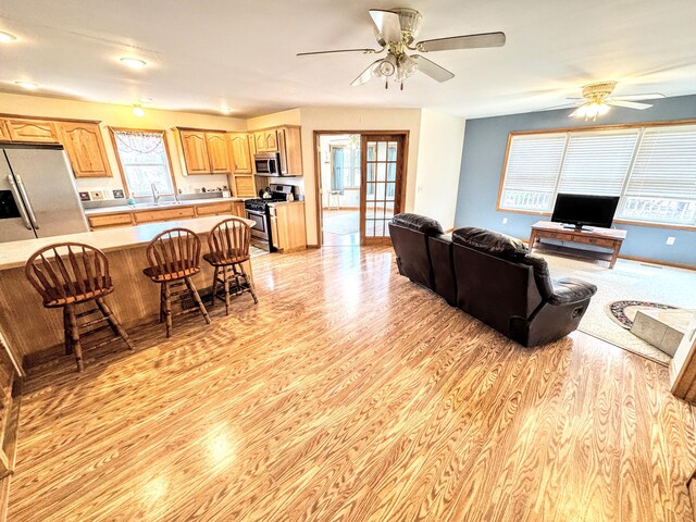 living area with ceiling fan and light wood-style floors