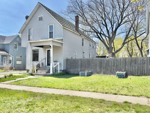 view of front of home with a chimney, a front lawn, and fence