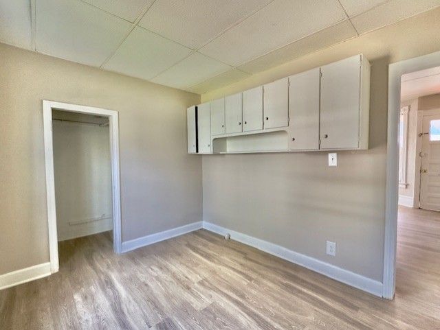 empty room featuring wood finished floors, baseboards, and a drop ceiling