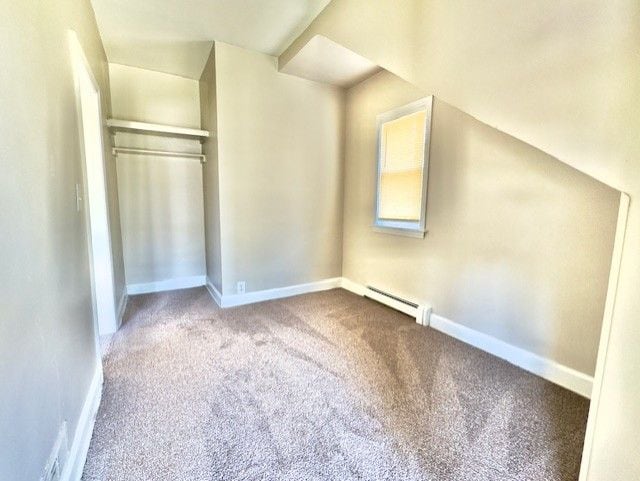 additional living space with a baseboard heating unit, baseboards, and carpet