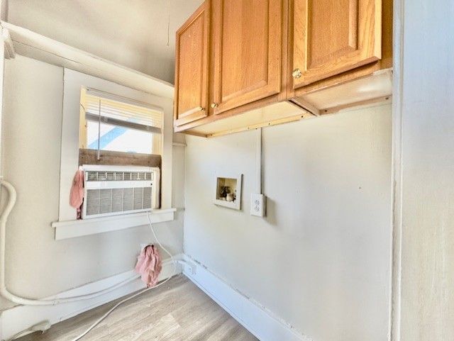 clothes washing area with cabinet space, light wood-style flooring, and hookup for a washing machine