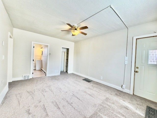 unfurnished bedroom featuring baseboards, visible vents, carpet, and a textured ceiling