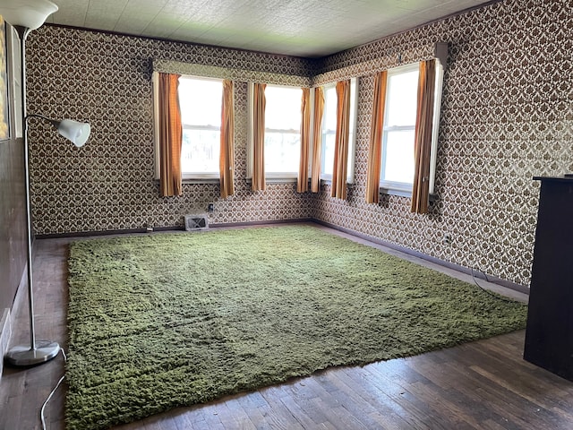 unfurnished room featuring wallpapered walls, wood-type flooring, and baseboards