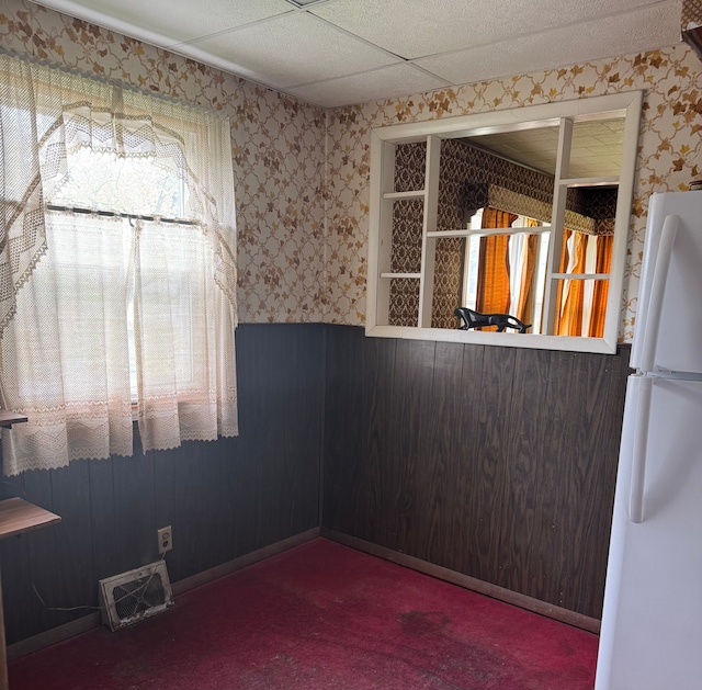 unfurnished dining area featuring wallpapered walls, carpet, and wainscoting