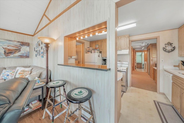 kitchen with a breakfast bar, open floor plan, white appliances, lofted ceiling, and light floors