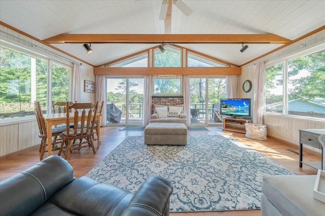 living area featuring lofted ceiling with beams, a ceiling fan, wood walls, and wood finished floors