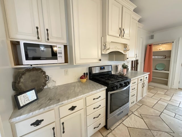 323 N Marshall Ave, Marshall, MI 49068 - kitchen featuring stainless steel range with gas cooktop, stone tile floors, white microwave, premium range hood, and visible vents