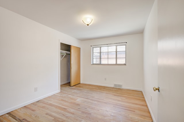 unfurnished bedroom featuring baseboards, visible vents, wood finished floors, and a closet