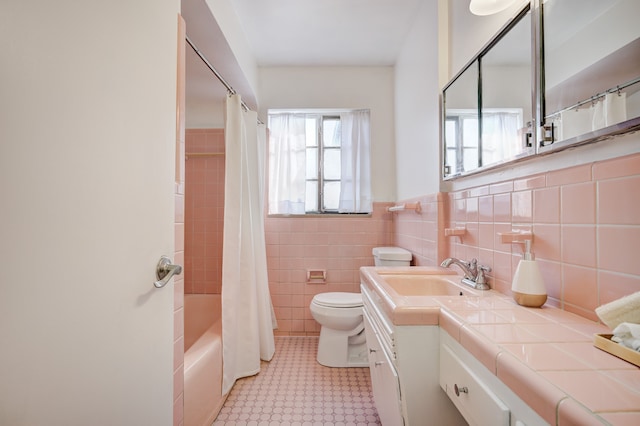 full bath featuring vanity, toilet, a wainscoted wall, tile walls, and shower / tub combo