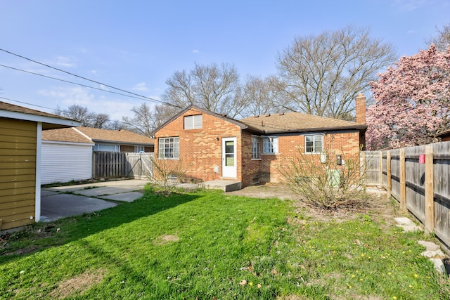 back of house with a fenced backyard, a lawn, a patio area, and brick siding