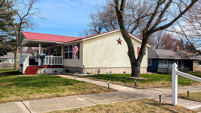 view of front of home with fence, a porch, metal roof, and a front yard