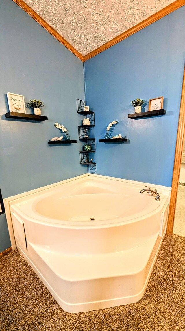 bathroom featuring a bath, a textured ceiling, and ornamental molding